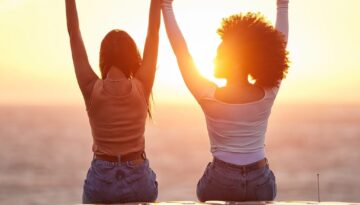 Sunset, women sitting on a car and at the beach with back view for carefree or peace. Freedom or adventure, summer vacation or holiday break and travel with female people at sea happy together