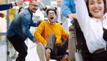 Friendly work team ride chairs in office room cheerfully excite
