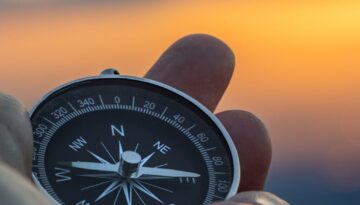 compass in hand with sunset sky on the background